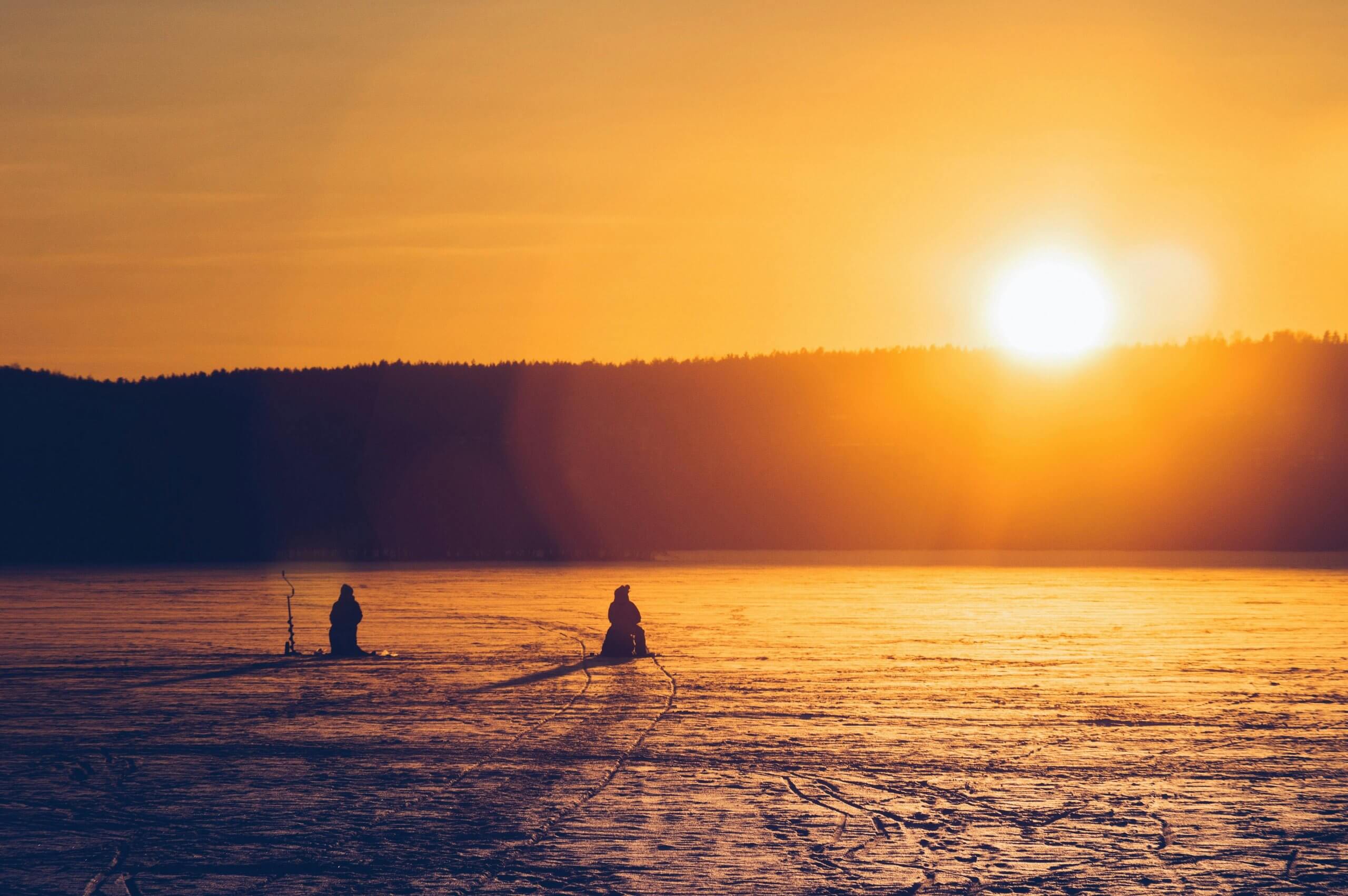 deux pêcheurs sur la glace au coucher du soleil