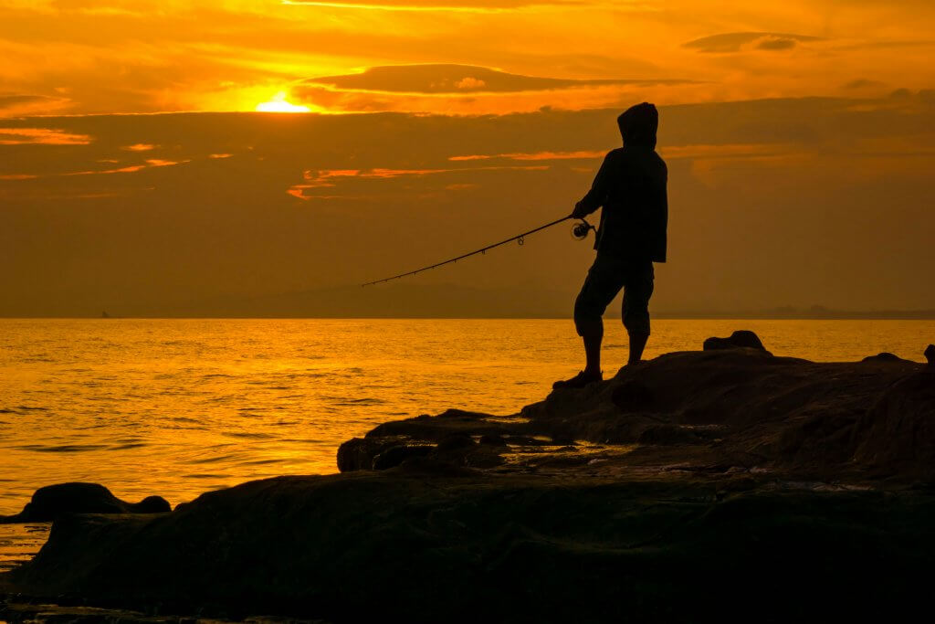 Pêcheur en surfcasting au coucher du soleil. credit : natsuki