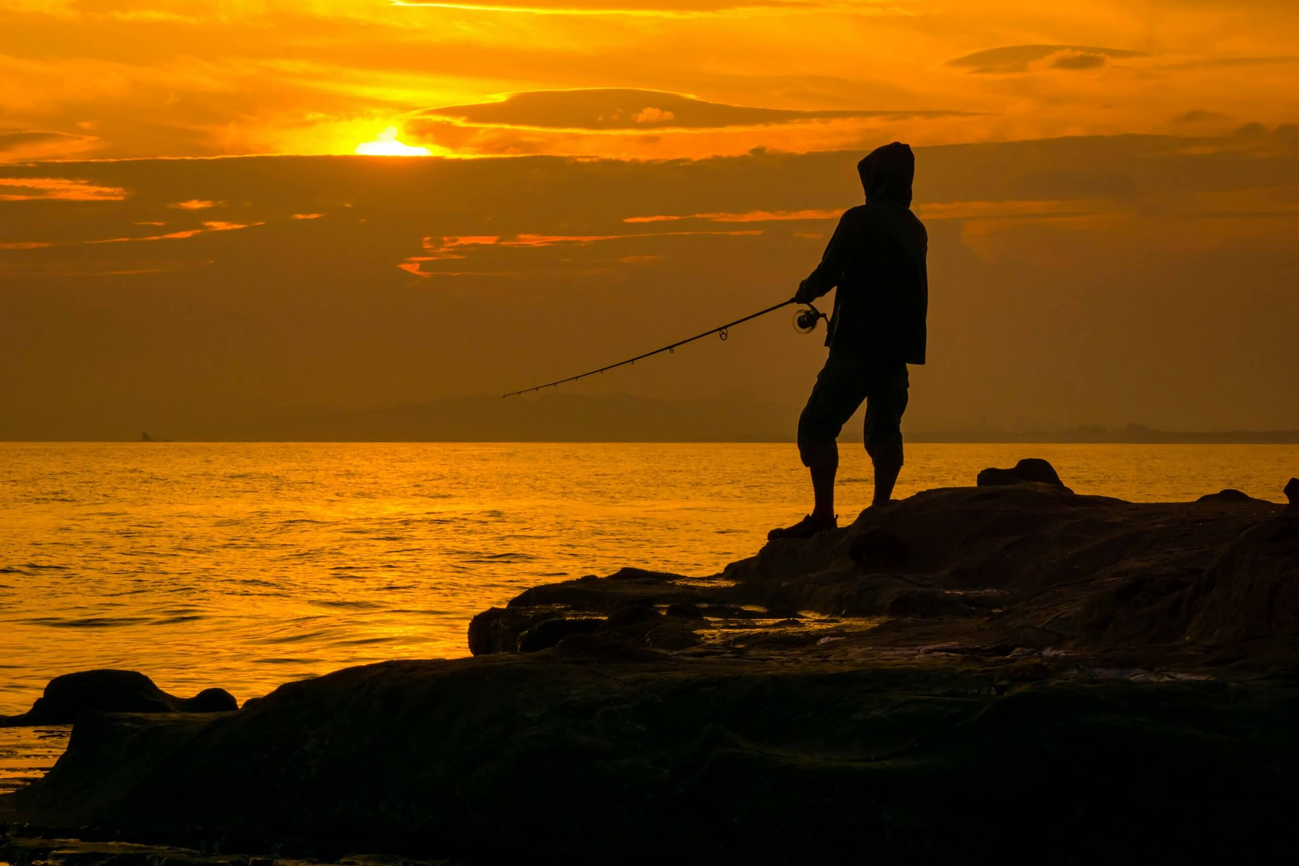 Pêcheur en surfcasting au coucher du soleil. credit : natsuki
