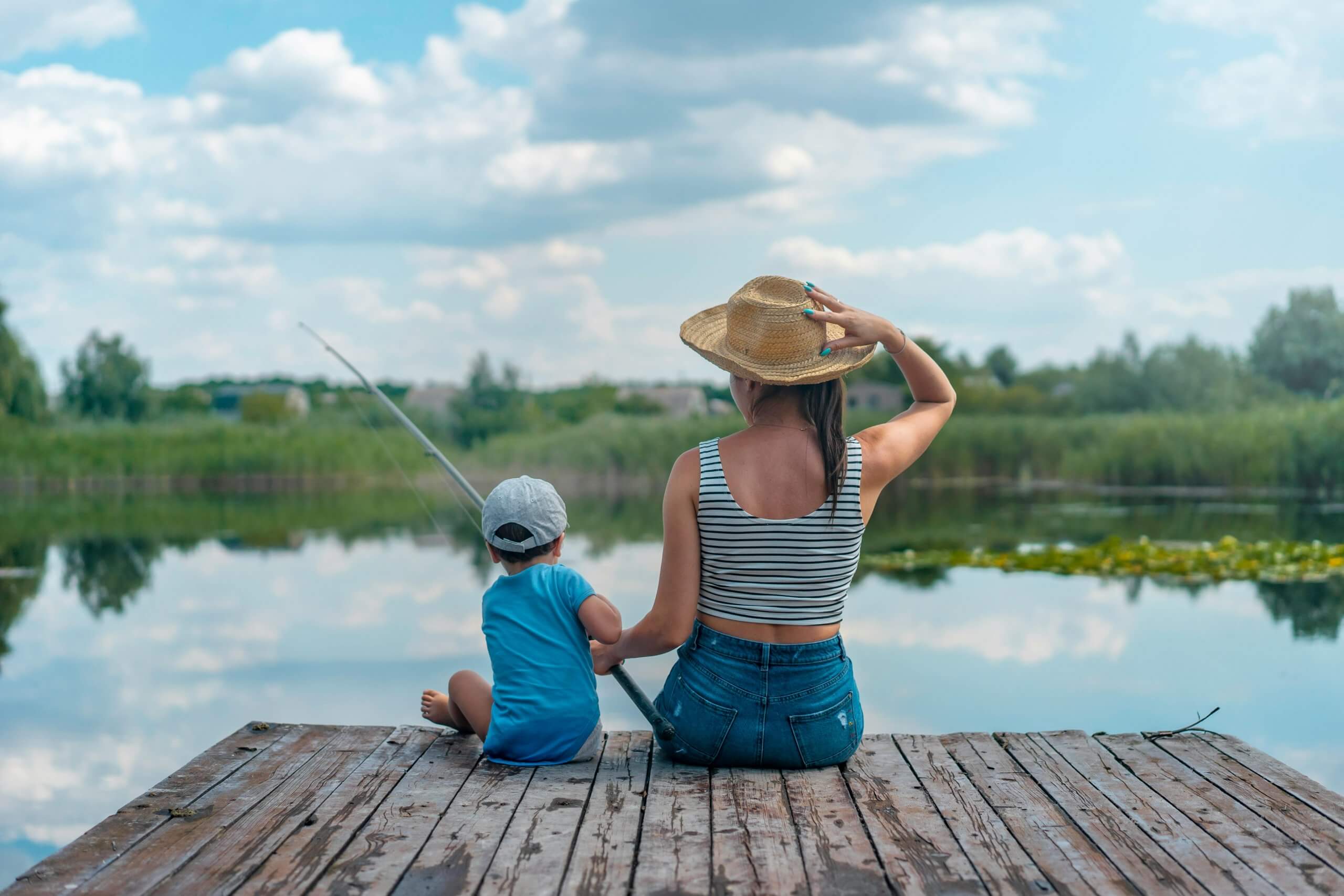 enfant qui pêche avec sa maman sur le bord d 'un lac - premier moulinet de peche - débutant