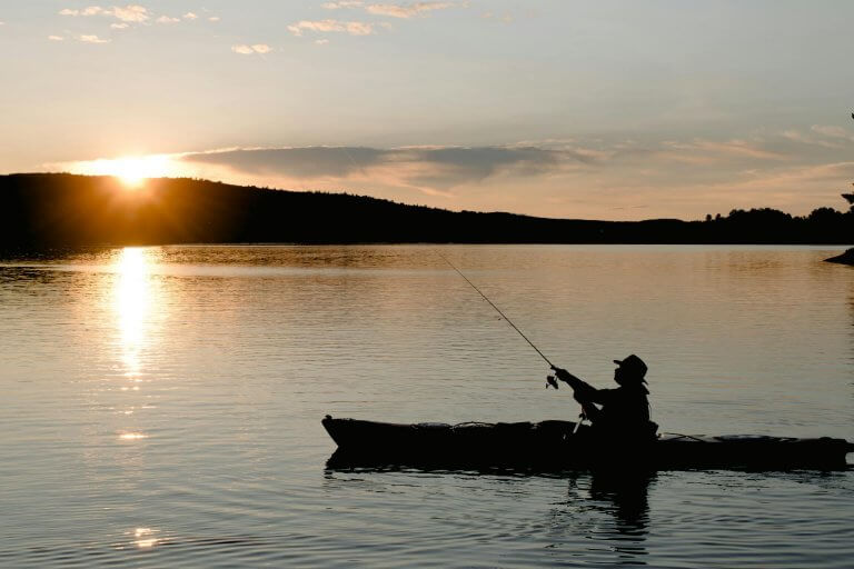 pêcheur en kayak au coucher du soleil
